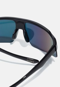Schwarze Sonnenbrille mit elegantem Design, ausgestattet mit Verlaufslinsen, die von Blau nach Lila übergehen. Das Gestell ist kantig und hat eine glänzende Oberfläche.