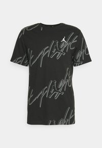 T-shirt noir à manches courtes avec des motifs répétés en gris "Flight" et le logo Jumpman, petit logo Jumpman blanc sur la poitrine.