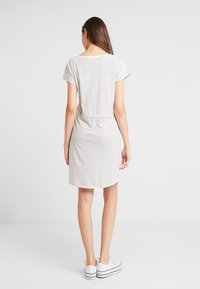 Randig bomullsklänning med korta ärmar, med en dragsko i midjan och knälång nederkant. Färgerna inkluderar vitt med mörka ränder.