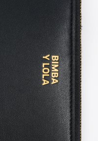 Czarny portfel o teksturowanej fakturze z złotym, wytłoczonym logo "BIMBA Y LOLA", z zapięciem na zamek błyskawiczny na górze.
