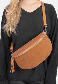 Orange Cord-Ripstop-Schultertasche mit geschwungenem Design, silbernem Reißverschluss und braunem Tragegurt, ausgestattet mit dekorativen Quasten am Reißverschluss-Anhänger.