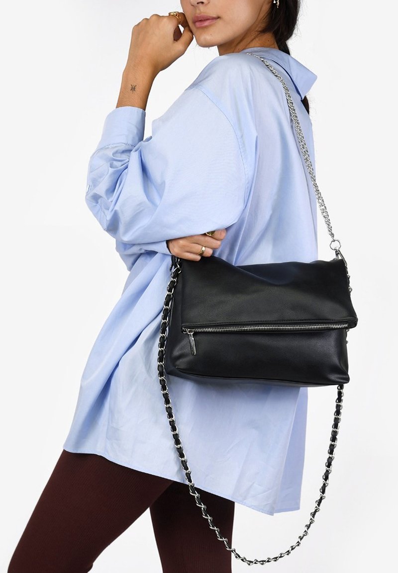 Borsa a tracolla in pelle nera con tasca frontale con zip e tracolla a catena. La borsa è rettangolare, leggermente piegata e con una texture.