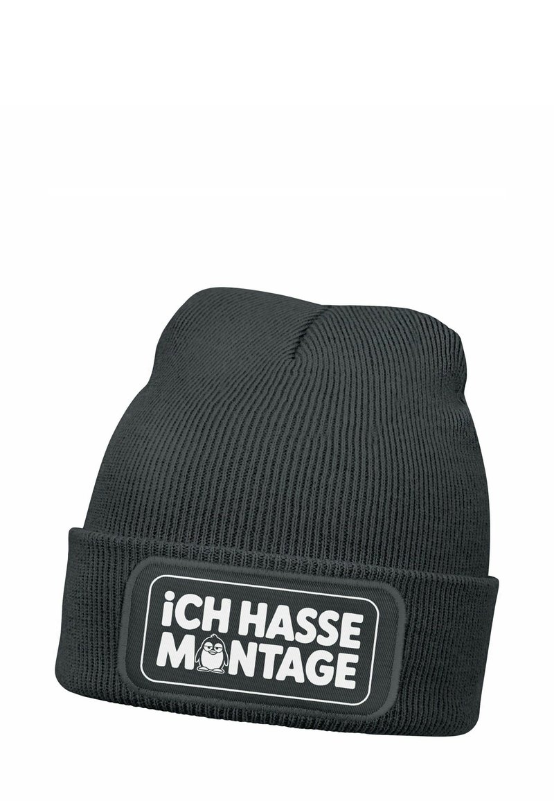 Black knit beanie with a ribbed texture. Features a rectangular patch in white with the text "iCH HASSE MONTAGE" and a cartoon penguin illustration.