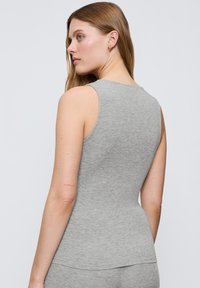 Szara bezrękawnik wykonana z miękkiego materiału, o dopasowanym kształcie i gładkiej strukturze. Zauważalny detal: subtelne przeszycia wzdłuż krawędzi.