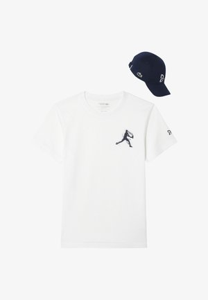 T-shirt bianca in cotone con una grafica blu scuro di una figura in movimento sul petto, abbinata a un cappellino da baseball blu scuro con un logo.