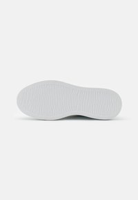 Semelle d'une chaussure en caoutchouc blanc, présentant un motif texturé ondulé pour l'adhérence et la flexibilité. Forme plate et arrondie sans détails supplémentaires.