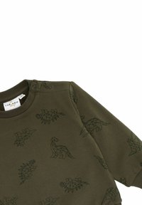 Sudadera verde oliva con patrones de dinosaurios geométricos negros, puños acanalados y botones a presión en el hombro para facilitar el vestir.