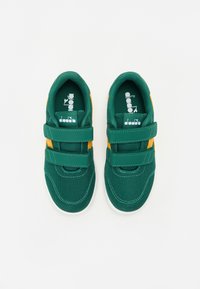 Grønne mesh sneakers med oransje detaljer, utstyrt med to borrelåsremmer og en hvit gummisåle. Merkenavn synlig på innersålene.