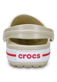 Crocs slide sandal in light beige with a thick strap and a textured footbed. Features a white band with red accents and logo on the back.