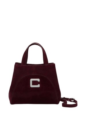 Sac à main en daim bordeaux foncé avec doubles poignées, logo argenté en forme de « C » à l'avant, et bandoulière détachable sur fond blanc.