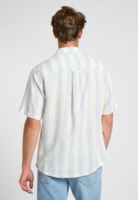 Camicia a maniche corte a righe blu chiaro e crema con vestibilità comoda, spalle a yoke e orlo dritto. Realizzata in un tessuto testurizzato.