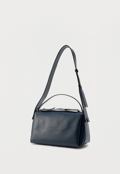 Navy blue leather handbag with a structured shape, adjustable shoulder strap, and a top handle. Smooth texture and minimalistic design.