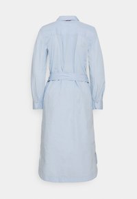 Ljusblå skjortklänning med långa ärmar, krage och bälte i midjan. Har en rak passform och sidoklipp i fållen.