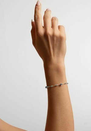 Silberarmband mit kleinen, runden Perlen mit glatter Oberfläche, getragen an einem Handgelenk mit natürlichem Hautton, Hand nach oben gerichtet.