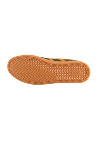 Suola di sneaker con un design in gomma testurizzata arancione. Presenta una tomaia in tessuto verde con strisce arancioni e logo del marchio.
