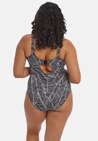 Jednodílné plavky s černobílým listovým vzorem, nastavitelnými ramínky, otevřeným zadním dílem a přiléhavým střihem, které ukazují hladkou strukturu látky.