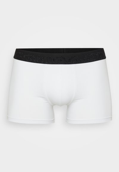 Hvide boxer shorts med et sort elastisk bælte, der har tekstureret skrift. Glat stof, tætsiddende design og medium-længde ben.
