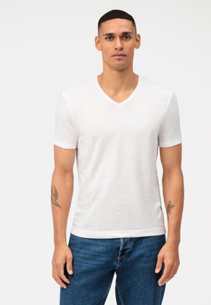 Witte korte mouwen V-hals t-shirt van lichtgewicht stof, met een soepele textuur en subtiel heather patroon, gecombineerd met een blauwe spijkerbroek.