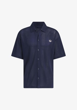 Chemise bleu marine à manches courtes avec boutons, tissu perforé et petit logo blanc sur la poitrine gauche.