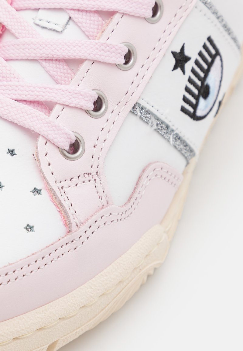Rosa Leder-Sneaker mit weißen Akzenten, ausgestattet mit silbernen Stern-Details und einem gestickten Augendesign. Runde Zehenpartie und strukturierte Laufsohle.