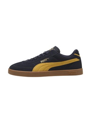 Marineblå Puma sneakers med sennepsgul sidebane, brun sål og guld Puma-logo på siden og på tungen, set fra den ydre side.