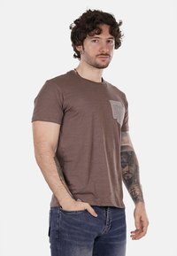 T-shirt marrone a maniche corte con tasca a contrasto grigia testurizzata, scollo a girocollo e vestibilità rilassata, realizzata in tessuto morbido.