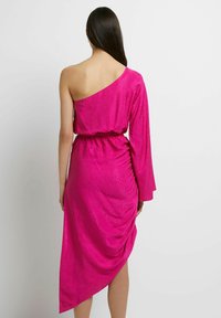Asymetrické, jednoramenné šaty v jasně růžové látce s texturou hadího vzoru, s nařaseným páskem a draped detaily na zadní straně.