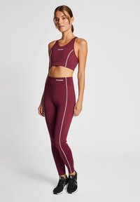 Bordowy zestaw biustonosza sportowego i legginsów z białymi detalami, dopasowany krój, miękka tekstura i elastyczny pas. Odpowiedni do aktywności sportowych.