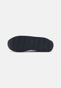 Suola di sneaker in gomma navy con un motivo testurizzato che presenta forme rettangolari e quadrate, punta arrotondata e dettaglio del logo in rilievo.