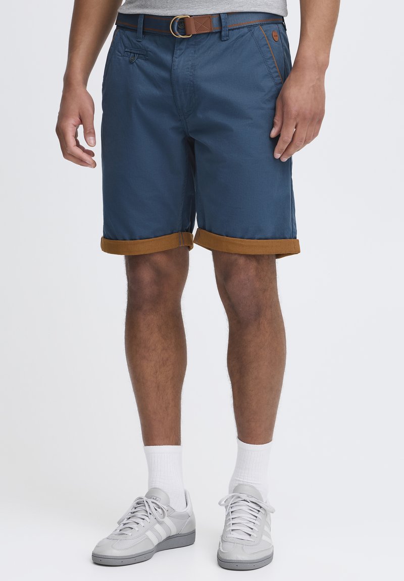 Menns marineblå shorts med brune mansjetter, med knapp- og glidelås-lukking. Laget av lett materiale, designet med sidelommer.