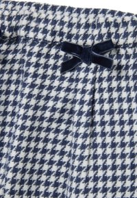 Blauw en wit houndstooth stof met een zachte textuur, voorzien van een fluwelen strikaccent op de tailleband en een plooidetail.
