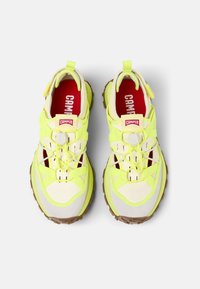 Lime green athletic shoes with a layered design, featuring a textured beige toe cap, adjustable elastic laces, and a brown outsole.