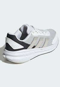 White athletic sneaker with mesh upper, grey suede accents, and black heel. Features a cushioned sole with visible tread patterns.