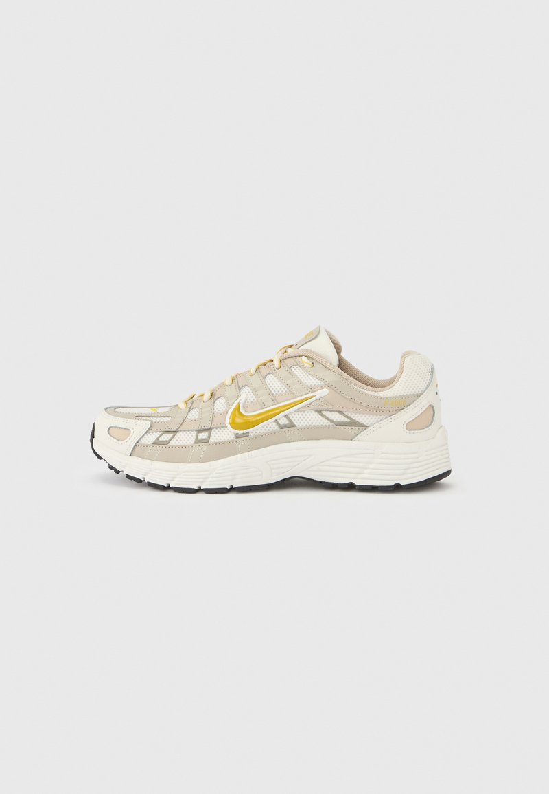 Μπεζ αθλητικό παπούτσι με επάνω μέρος από δίχτυ, κίτρινες λεπτομέρειες και επένδυση στην εξωτερική σόλα για άνεση. Υφασμένα πάνελ προσδίδουν καλύτερη αναπνοή και σχεδιασμό.