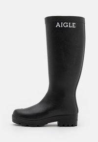 Botte de pluie noire en caoutchouc avec une texture lisse, une tige haute et une semelle robuste à nervures. Présente un logo AIGLE blanc à l'avant.