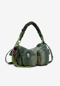Sac en tissu vert avec plusieurs poches zippées, une anse froncée et une base plate. Présente une finition texturée et des sangles contrastantes.