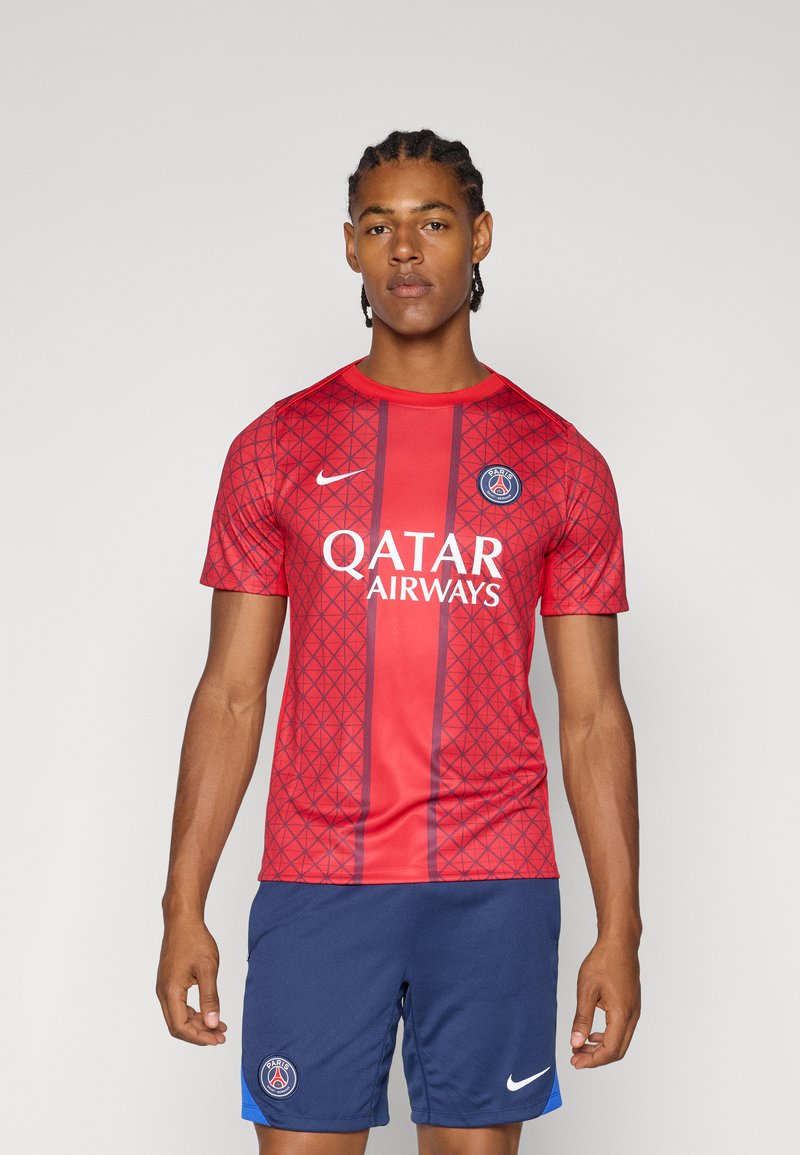 Rød kortærmet fodboldtrøje med geometrisk mønster, marineblå accenter og "Qatar Airways" logo, kombineret med marineblå shorts.