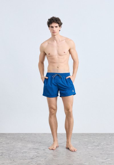 Siniset uima-alushousut, jotka on valmistettu kevyestä kankaasta. Niissä on joustava vyötärönauha nyöreillä, sivutaskut ja pieni logokoriste.