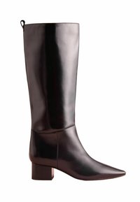 Czarne skórzane botki sięgające do kolan z wydłużonym noskiem i szerokim obcasem. Gładka tekstura, minimalne przeszycia i mała pętla na górze.