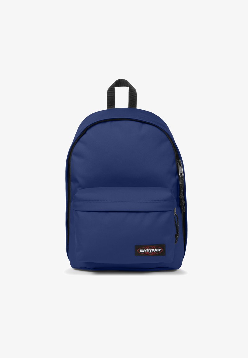 Mochila azul de nylon con una textura suave. Presenta un bolsillo frontal, cierre de cremallera y detalles en negro. Logo visible en la parte delantera.