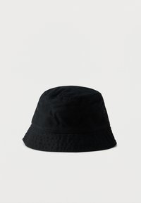 Μαύρο καπέλο τύπου bucket από ύφασμα με απαλή υφή. Διαθέτει στρογγυλεμένη κορυφή, φαρδύ γείσο και τρύπες στα πλάγια για αερισμό.