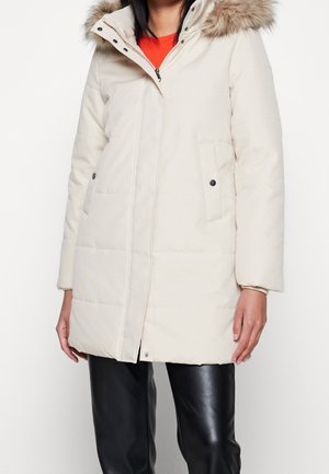 Beżowa ocieplana parka z kapturem z sztucznego futra, długie rękawy, zamek błyskawiczny z przodu, dwie boczne kieszenie, z czarnymi guzikami jako akcenty.