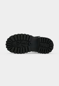 Semelle de bottes noire avec des rainures profondes et le mot "BUFFALO" en relief en grosses lettres en dessous.