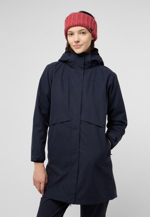 Marineblauwe waterdichte jas met capuchon en voorflapzakken. Heeft lange mouwen en een gladde textuur. Gecombineerd met een gestructureerde roze hoofdband.