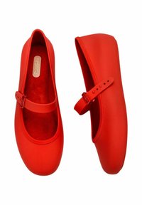 Bailarinas de goma rojas con punta redondeada, bordes elásticos y una sola cinta con hebilla ajustable. Forro interior suave.