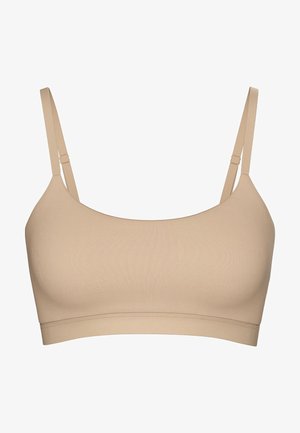 Beige trådløs bh med justerbare stropper, glat tekstur og et sømløst design. Har et bredt bånd for komfort og støtte.