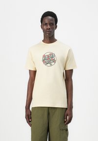 Cream short-sleeve t-shirt made of cotton, featuring a circular floral graphic design in red and green on the front. Plain back.