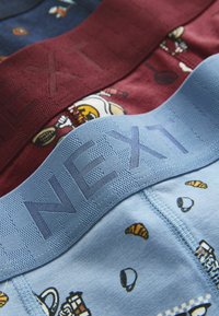 Trys bokserinių šortų poros mėlynos, bordo ir tamsiai mėlynos spalvų, su elastinėmis juostomis su užrašu „NEXT“ ir įvairiais žaismingais raštais.