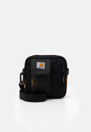 Kompakt Carhartt skuldertaske med sort bund, camouflageforlomme, lynlåslukket rum og justerbar rem, sat mod en ensfarvet baggrund.