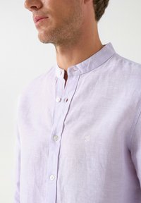 Licht lavendelkleurig, knoopsluiting shirt met een bandkraag, met subtiele textuur en een klein geborduurd logo op de linkerkant van de borst.